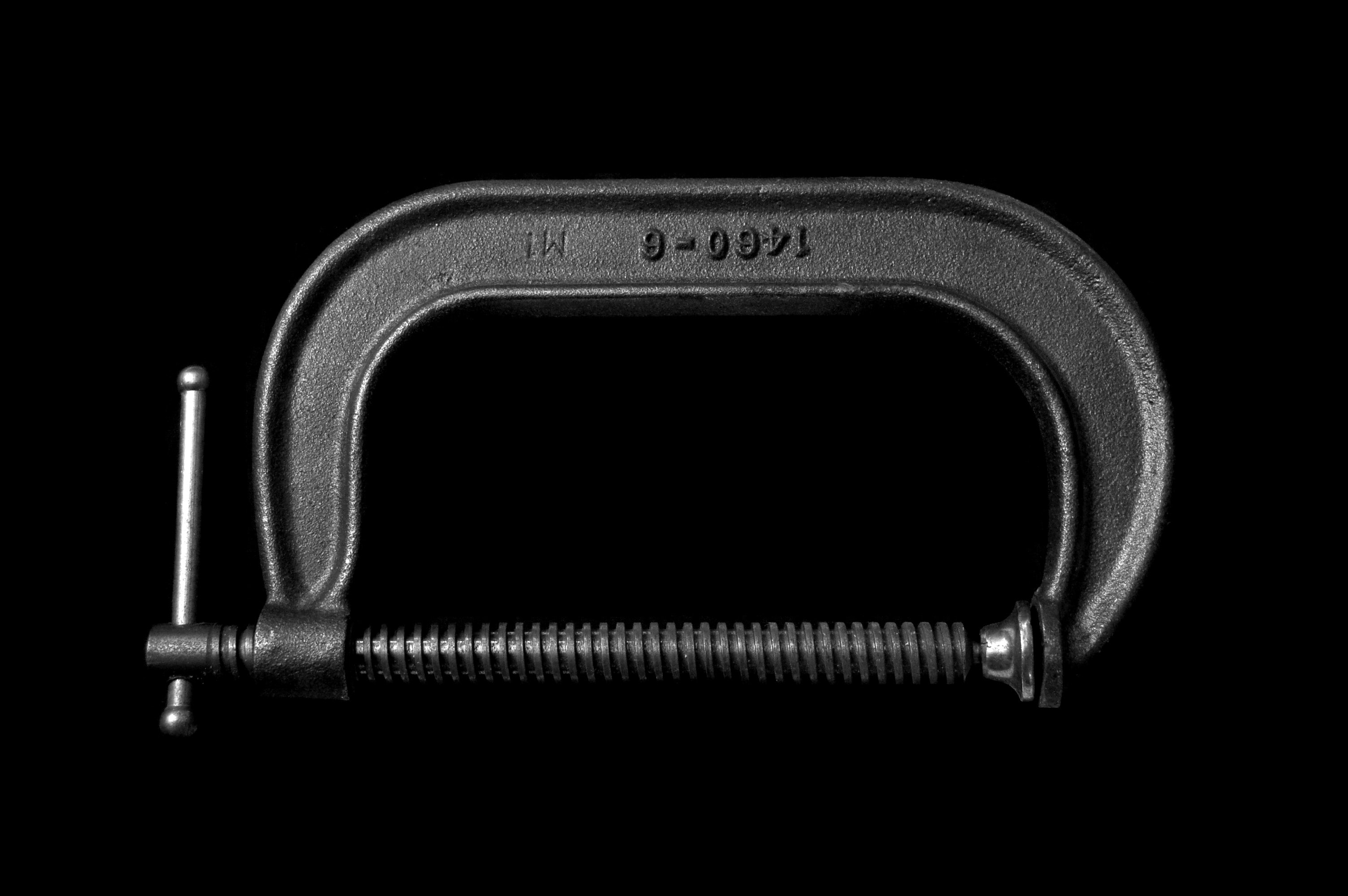 A black c-clamp on a black background